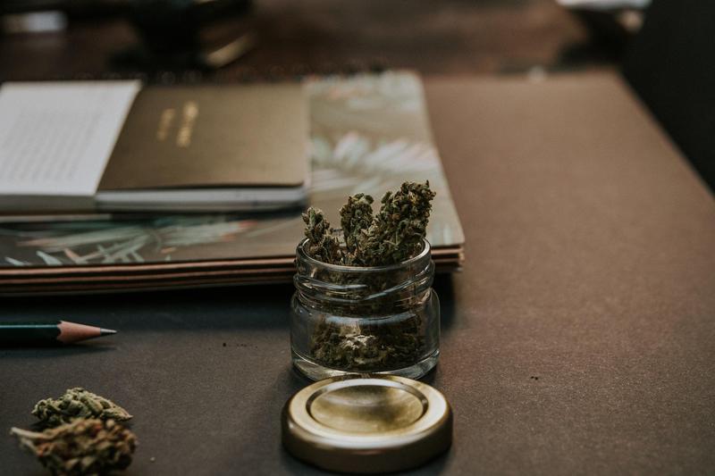 A photo of the cannabis plant in a small jar on a desk A photo of the cannabis plant in a small jar on a desk