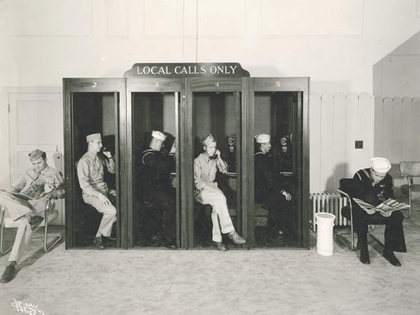 Archived photo of World War II soldiers each taking a call in phone booths