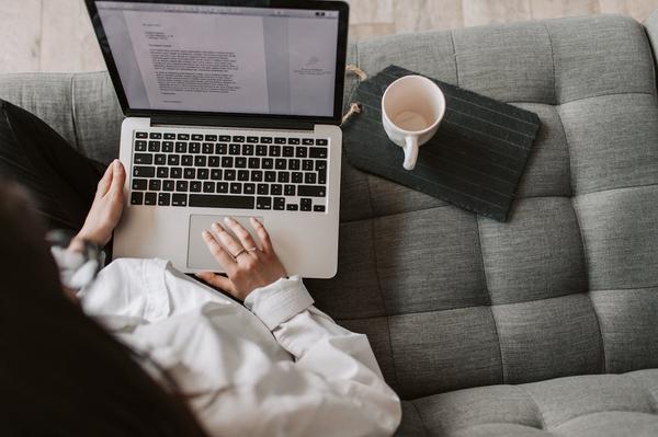 Woman performing content management services on a laptop next to a cup of coffee Woman performing content management services on a laptop next to a cup of coffee