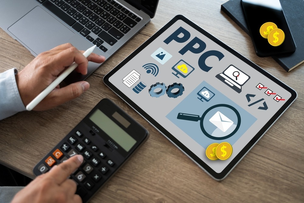 Person typing on a calculator with a screen that says PPC with icons