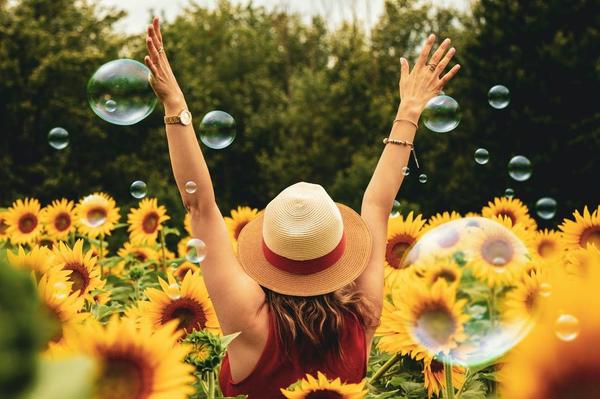 Woman in sunflower field surrounded by bubbles