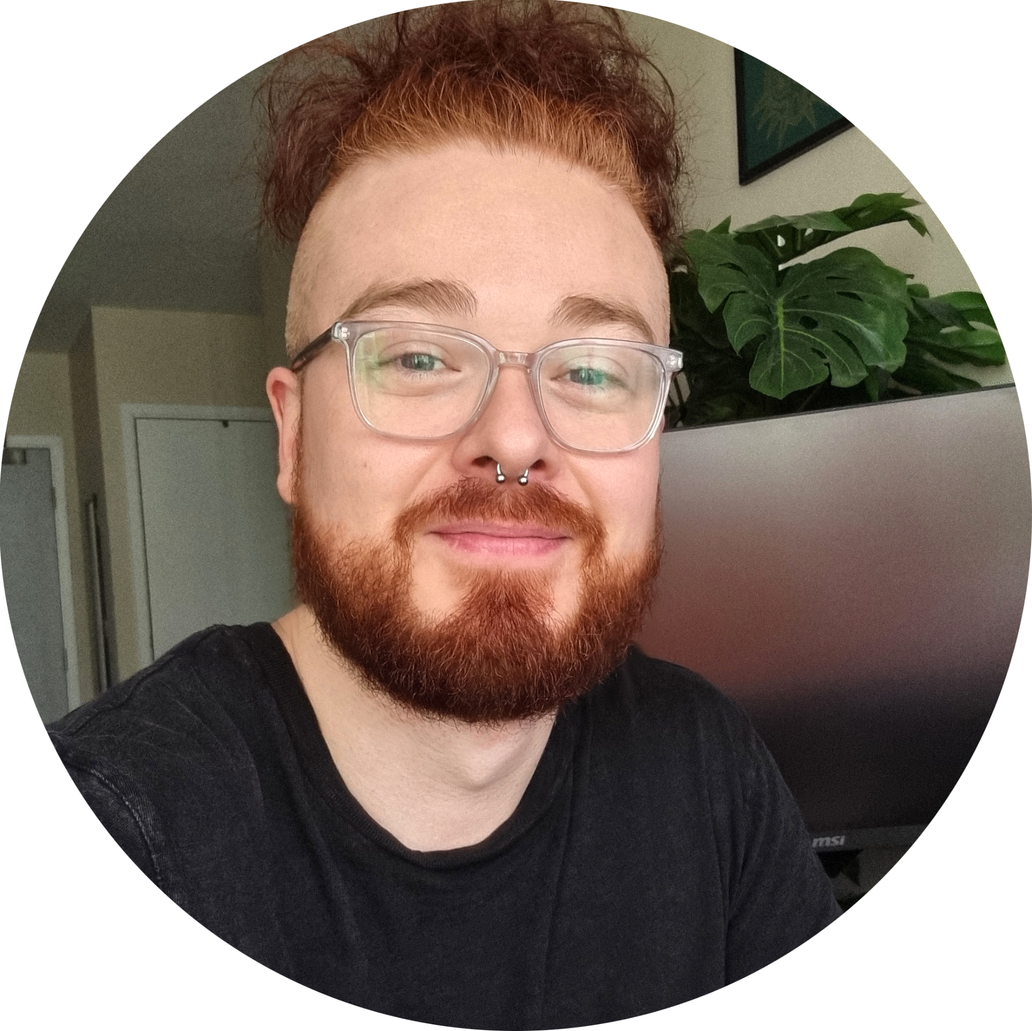 Circular photo of a smiling ginger bearded man with glasses
