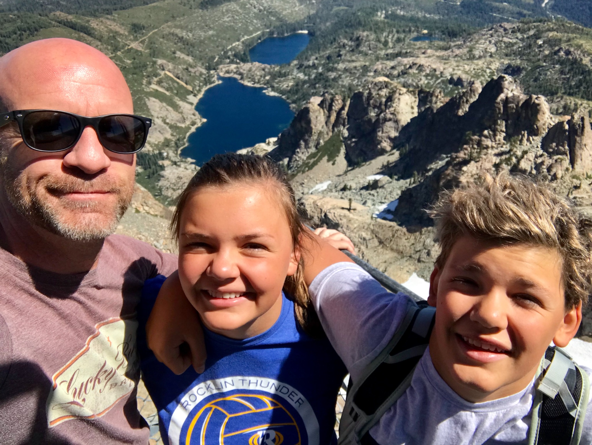 Photo of Paul Smith with Kids from the top of the lookout tower at the top of the Sierra Buttes in Tahoe National Forest. Upper and Lower Sardine Lake in the background far below.