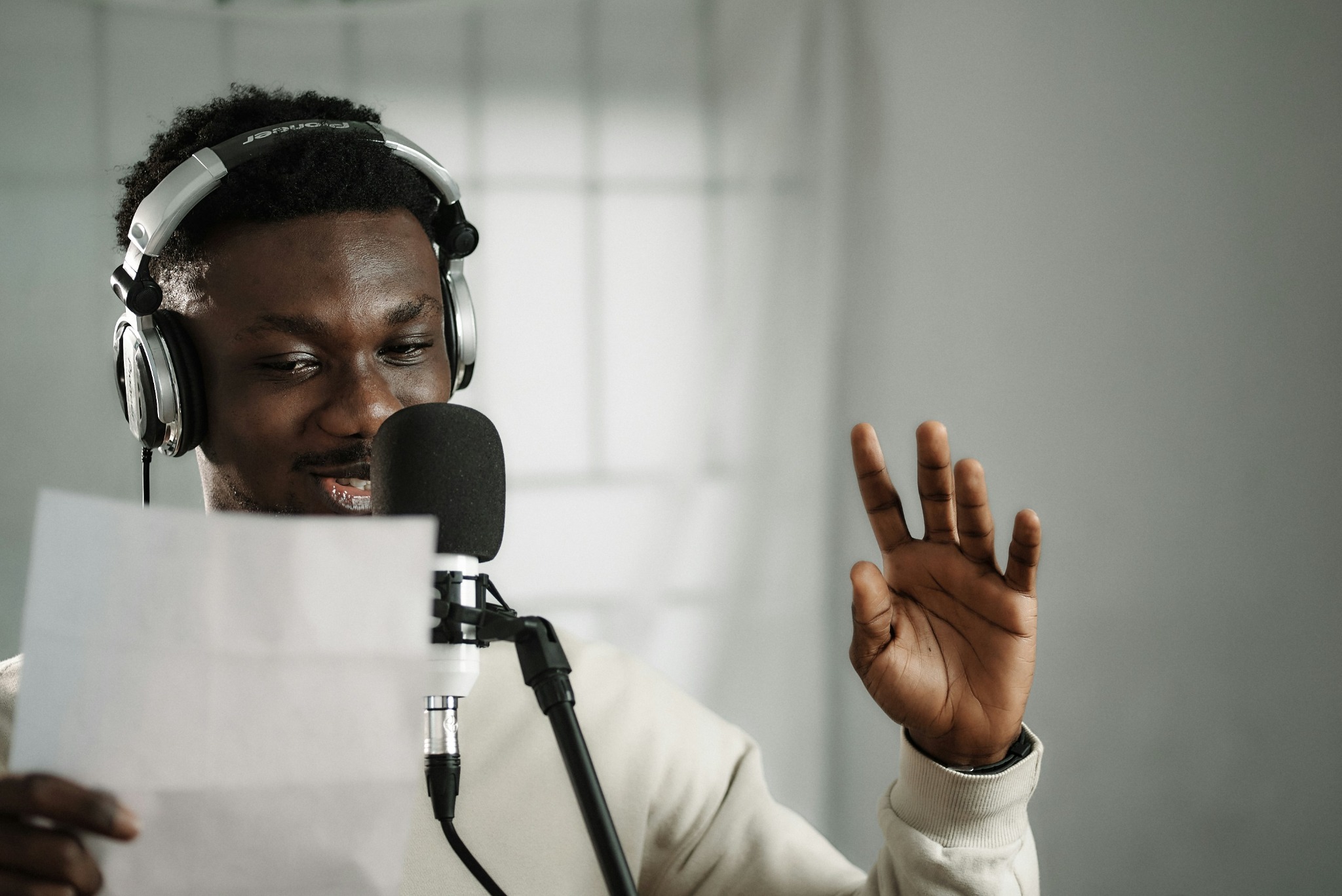 African male voice over artist recording a voice-over script with a condenser and Pioneer exclusive headphones.