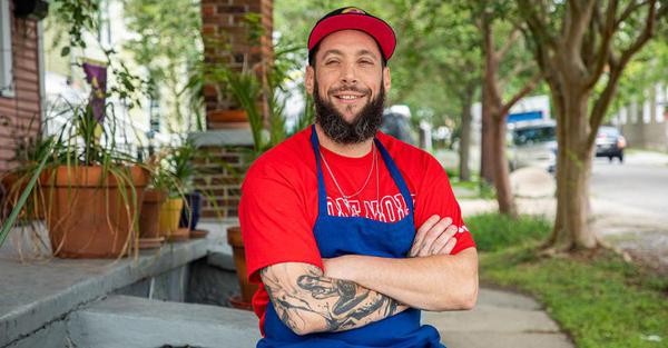 Ice cream man wearing blue apron and red shirt smiles for portrait