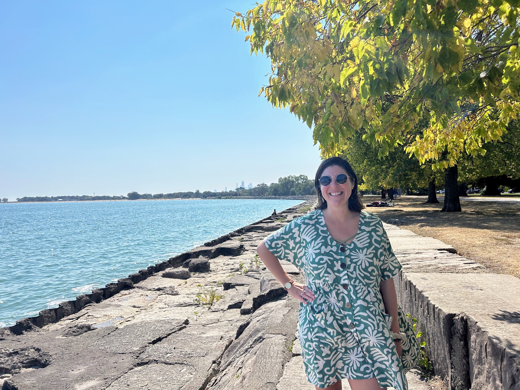 A woman in a green and white dress standing at the edge of a lake