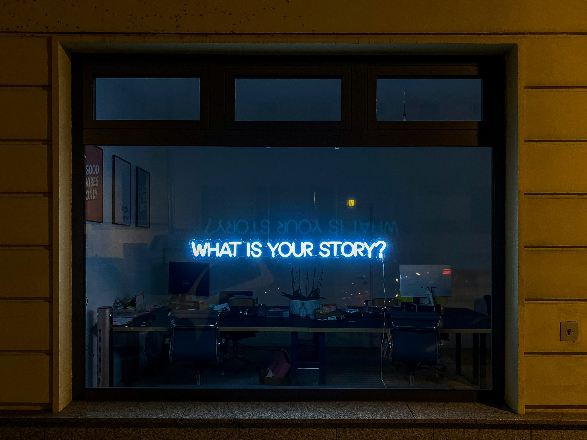 Window with neon sign: 'What is your story?'