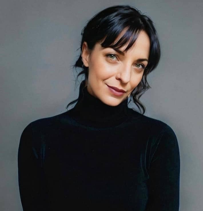 Headshot of Ashley Carter Cash in a black turtleneck staring lovingly into the camera with a tilted grin.