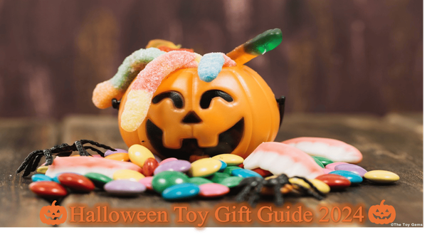 A plastic carved pumpkin on a table has jelly snakes and sweets/candy in and around the pumpkin. A few toy spiders are also amongst the mix.