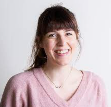 Woman with dark hair in pink jumper smiling