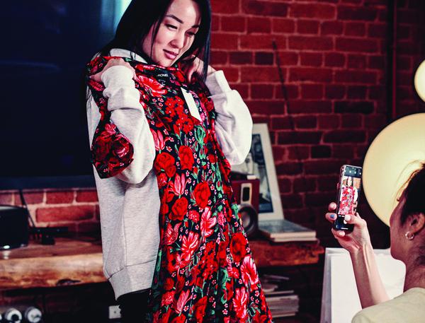 An asian woman holding up a red floral dress for a photo