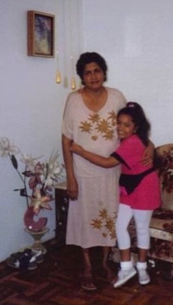 A photo from Krystal's childhood is seen. Krystal is seen jubilantly hugging Ruby, her maternal grandmother, in her aunt's home in NYC. Ruby wears a beige and gold dress, while Krystal wears white tights, with a pink top, a black fanny pack, and white socks and sneakers.