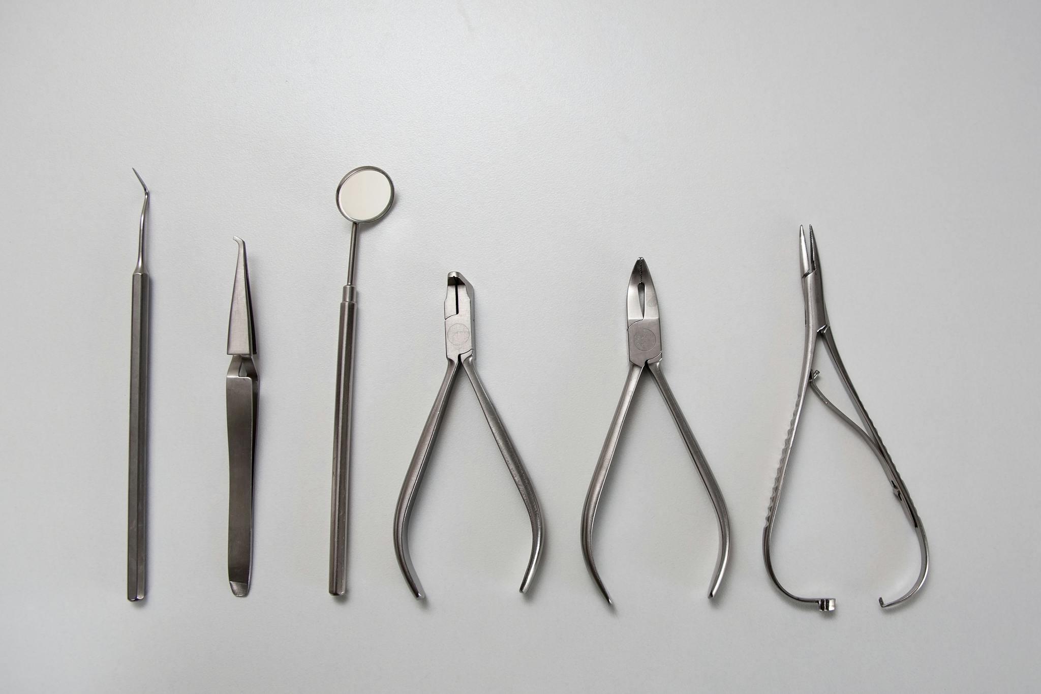 Against a white background, silver medical instruments are seen.