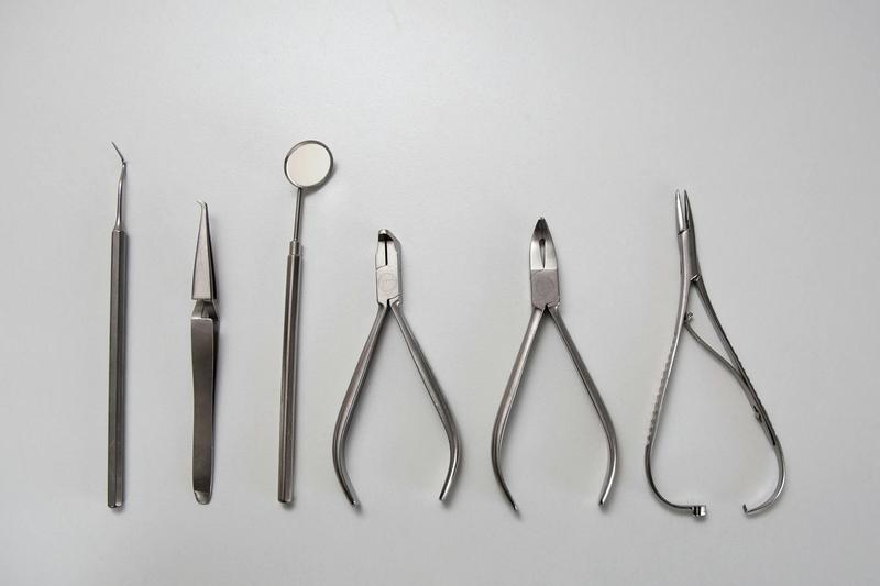 Against a white background, silver medical instruments are seen.