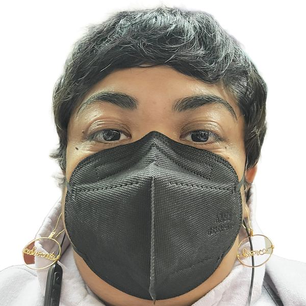 A selfie of Krystal Kavita Jagoo, a fat brown queer disabled immigrant woman and settler on Turtle Island, is seen. She is wearing a black KN95 mask, gold earrings that state "fierce" & "advocate," and a lavender hoodie. She has a black pixie cut, and black earphones.