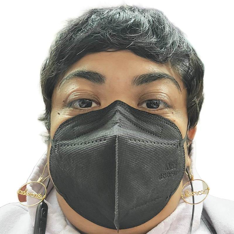 A selfie of Krystal Kavita Jagoo, a fat brown queer disabled immigrant woman and settler on Turtle Island, is seen. She is wearing a black KN95 mask, gold earrings that state "fierce" & "advocate," and a lavender hoodie. She has a black pixie cut, and black earphones.