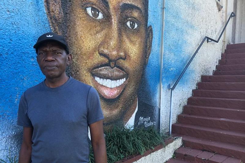 Standing in front of his mural of Ahmaud Arbery, is artist, Marvin Weeks.