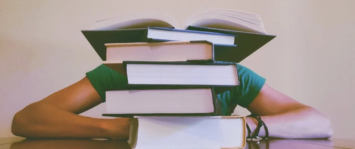 Student sleeping behind piled up books
