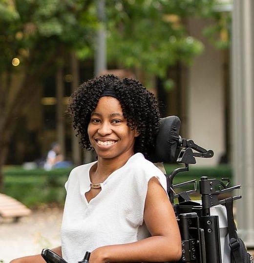 Nadira Bostic sitting in a motorized wheelchair and smiling.