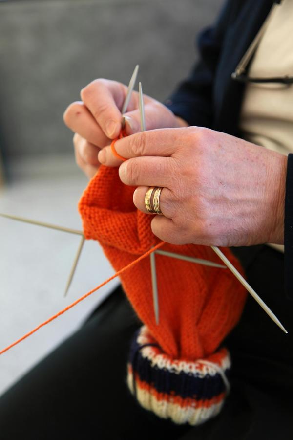 women's hands knitting a red hat