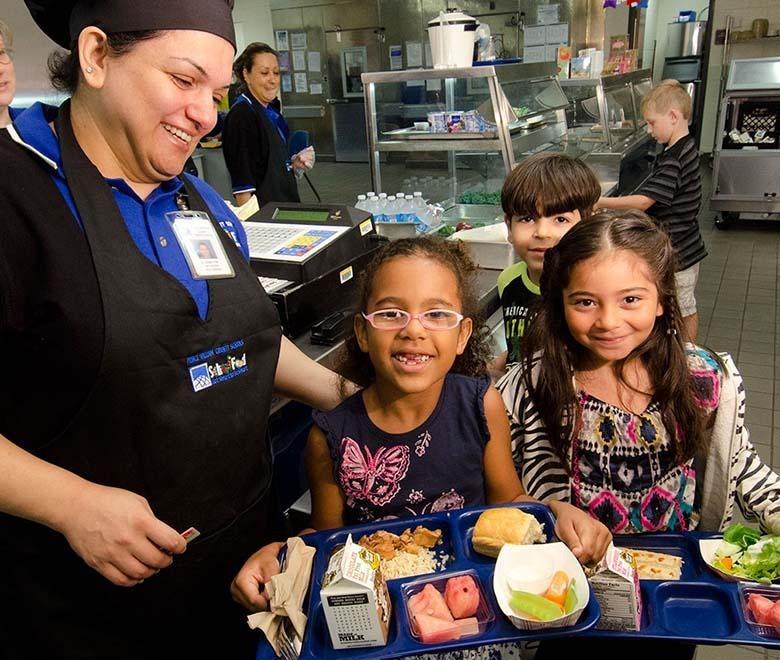 Lunch lady standing with school children.