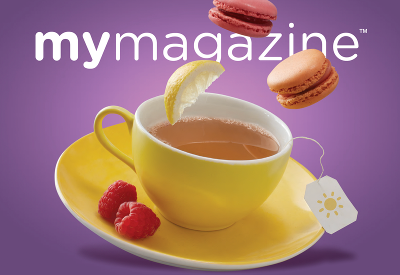 Cup of tea with macarons and raspberries next to the mug.