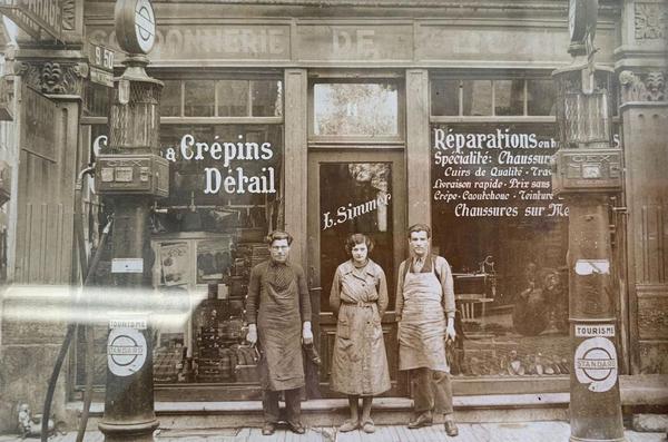 Deux hommes et une femme en tenue d'artisans posent devant une cordonnerie.