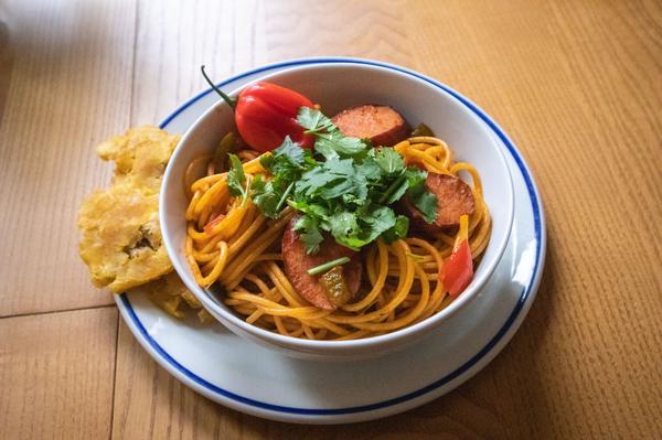 Haitian Spaghetti with sausage, scotch bonnet, cilantro and tostones in a bowl