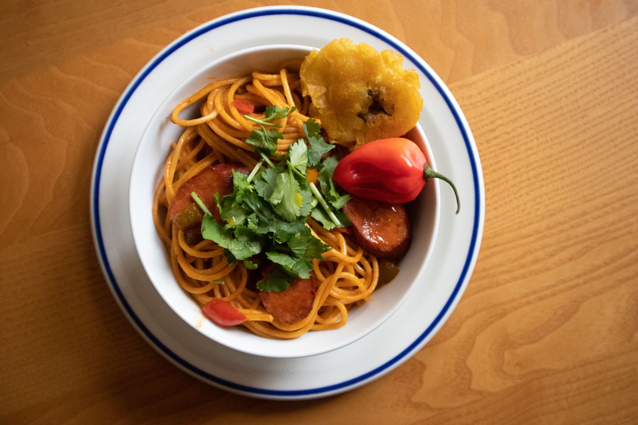 Haitian Spaghetti with sausage, scotch bonnet, cilantro and tostones in a bowl