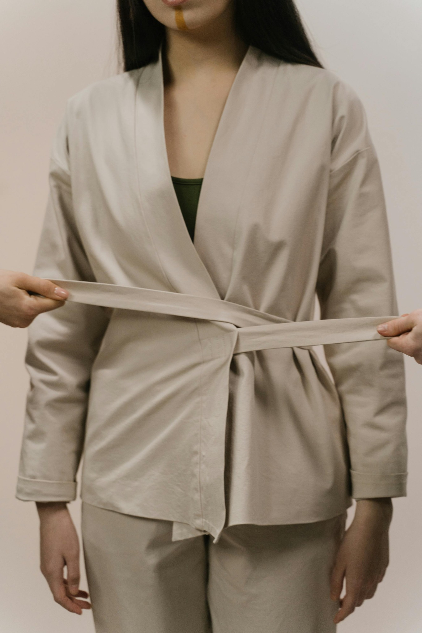 a woman wearing a shrug pulled from both sides by her  shrug's belt