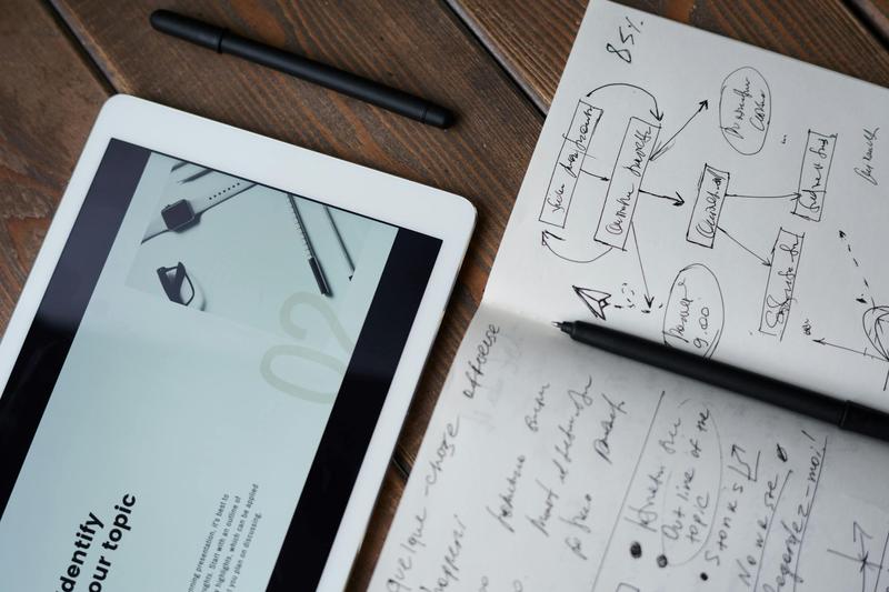 A tablet displaying presentation prep in front of handwritten notes.