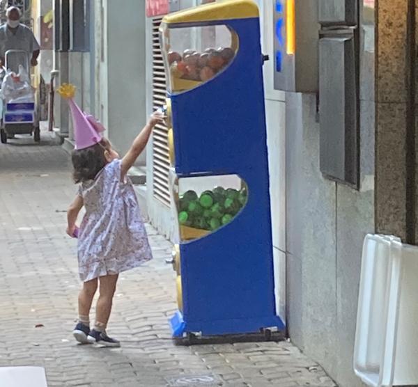 En lille pige rækker efter legetøj i automat