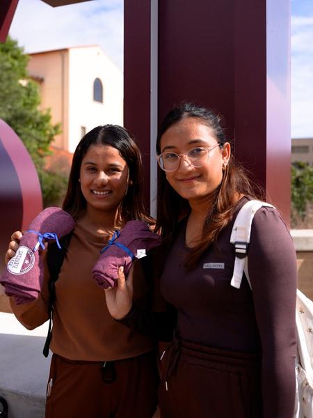 Two students smiling while holding t-shirts from The Graduate College