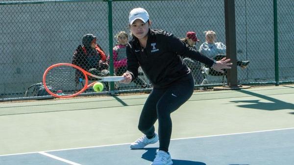Junior Temple tennis player Evie Wei hitting a ball in a doubles match against Rider University.