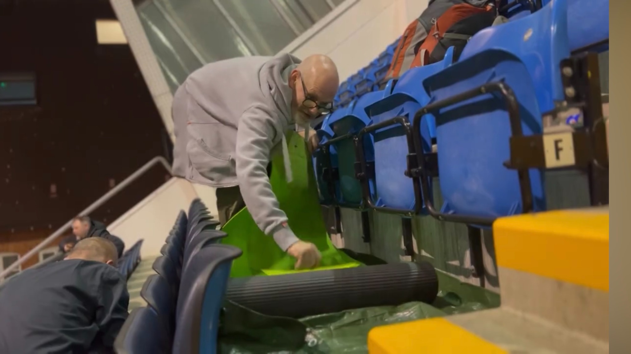 A man stood in the stands of Headingley Stadium rolling out a sleeping mat as he sets up his bed for the night