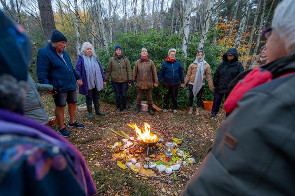 In this picture a group of people can be seen gathered around a fire holding hands