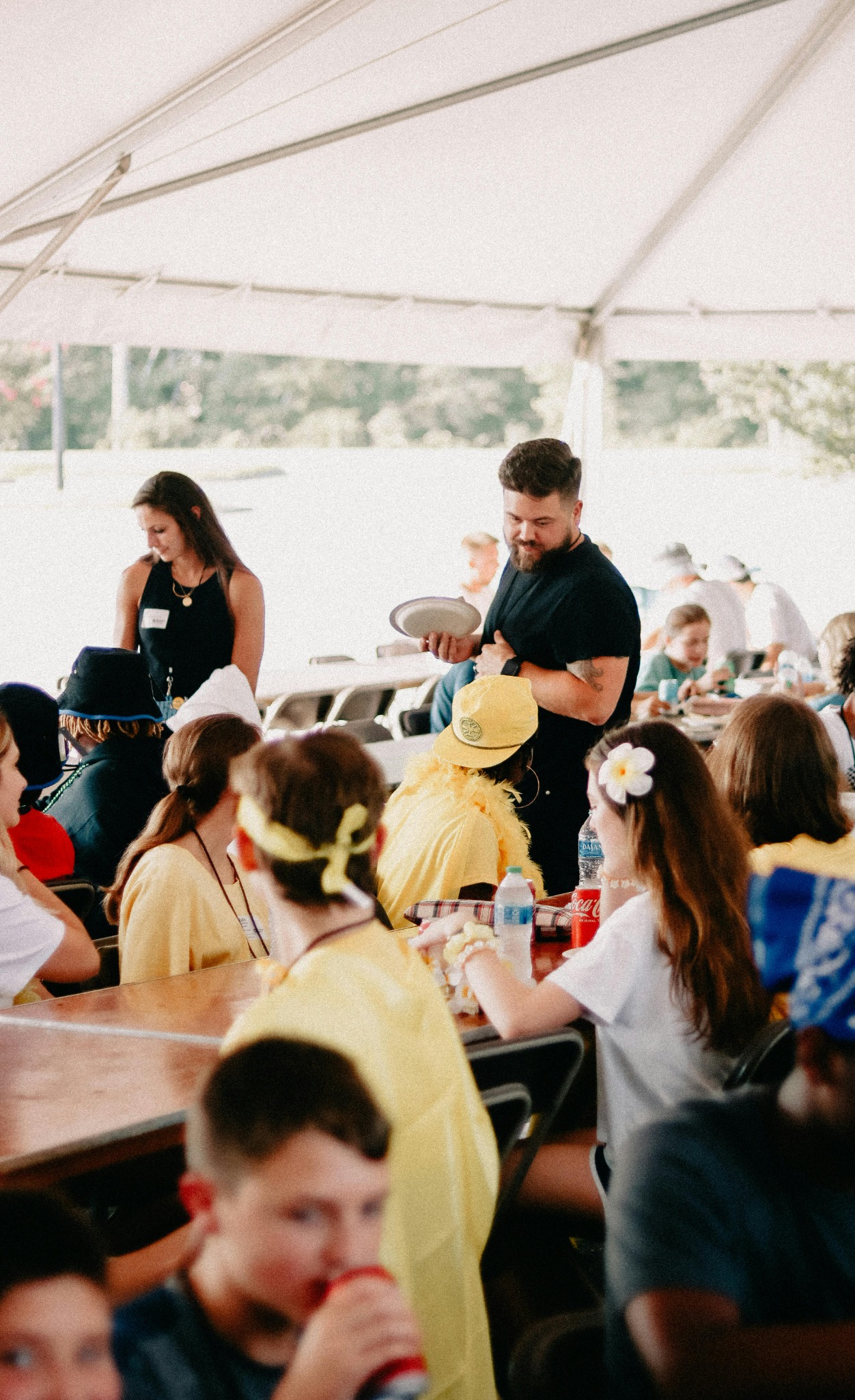 des gens qui sont assis à table sous un chapiteau, d'autres sont debout