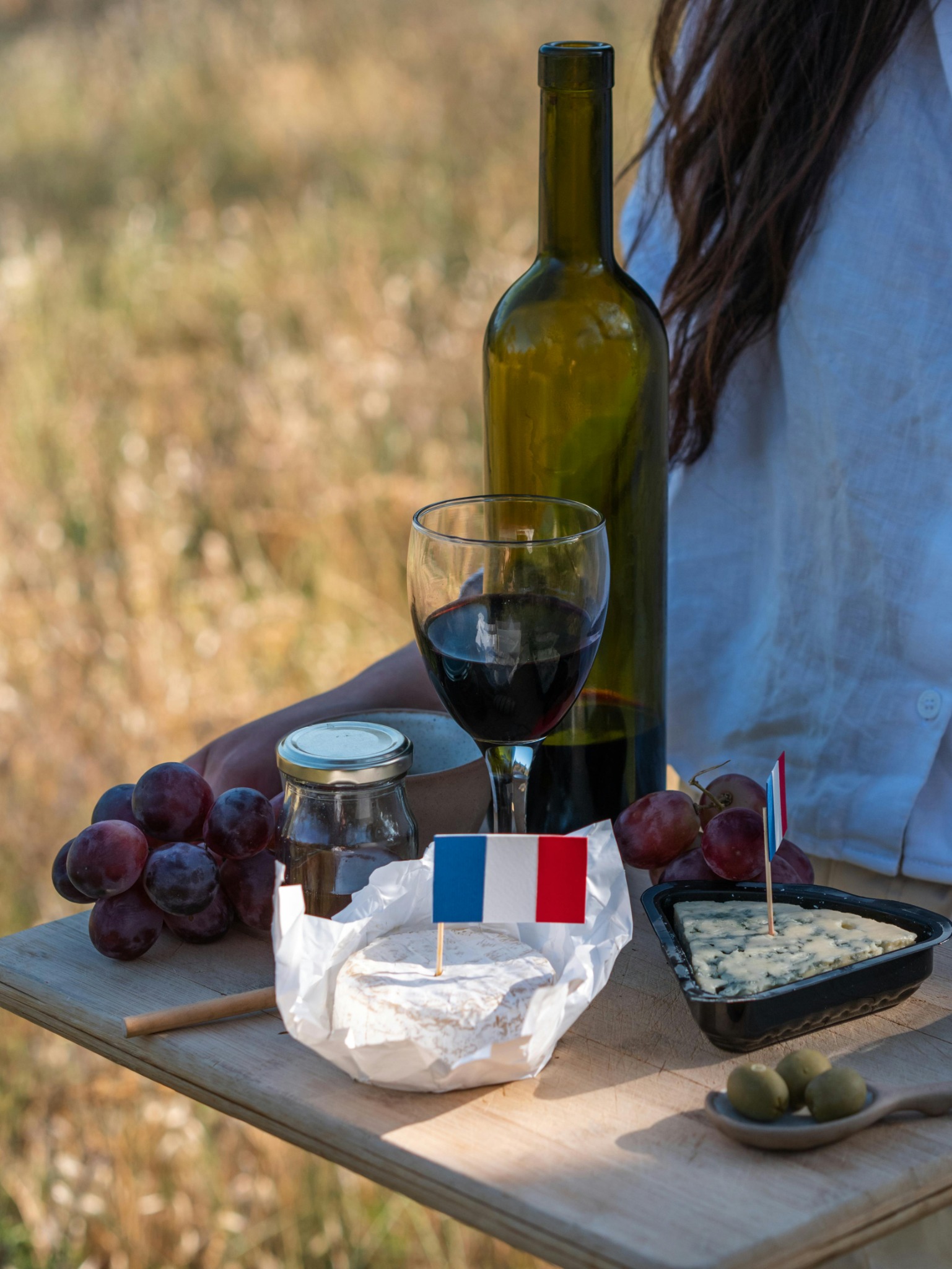 Plateau avec un verre de vin, bouteille, fromage, raison et olives