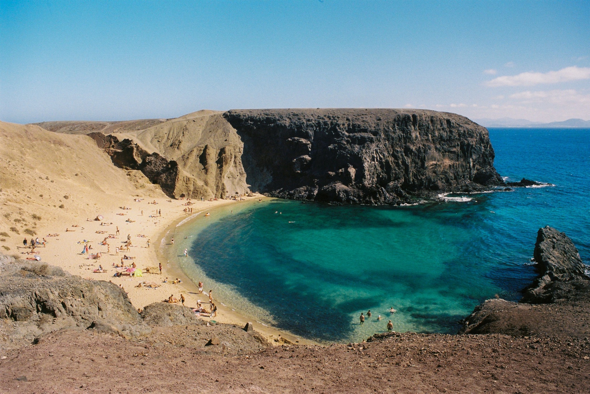 vu en hauteur d'une plage de sable avec la mer en contrebas, entourée de falaises