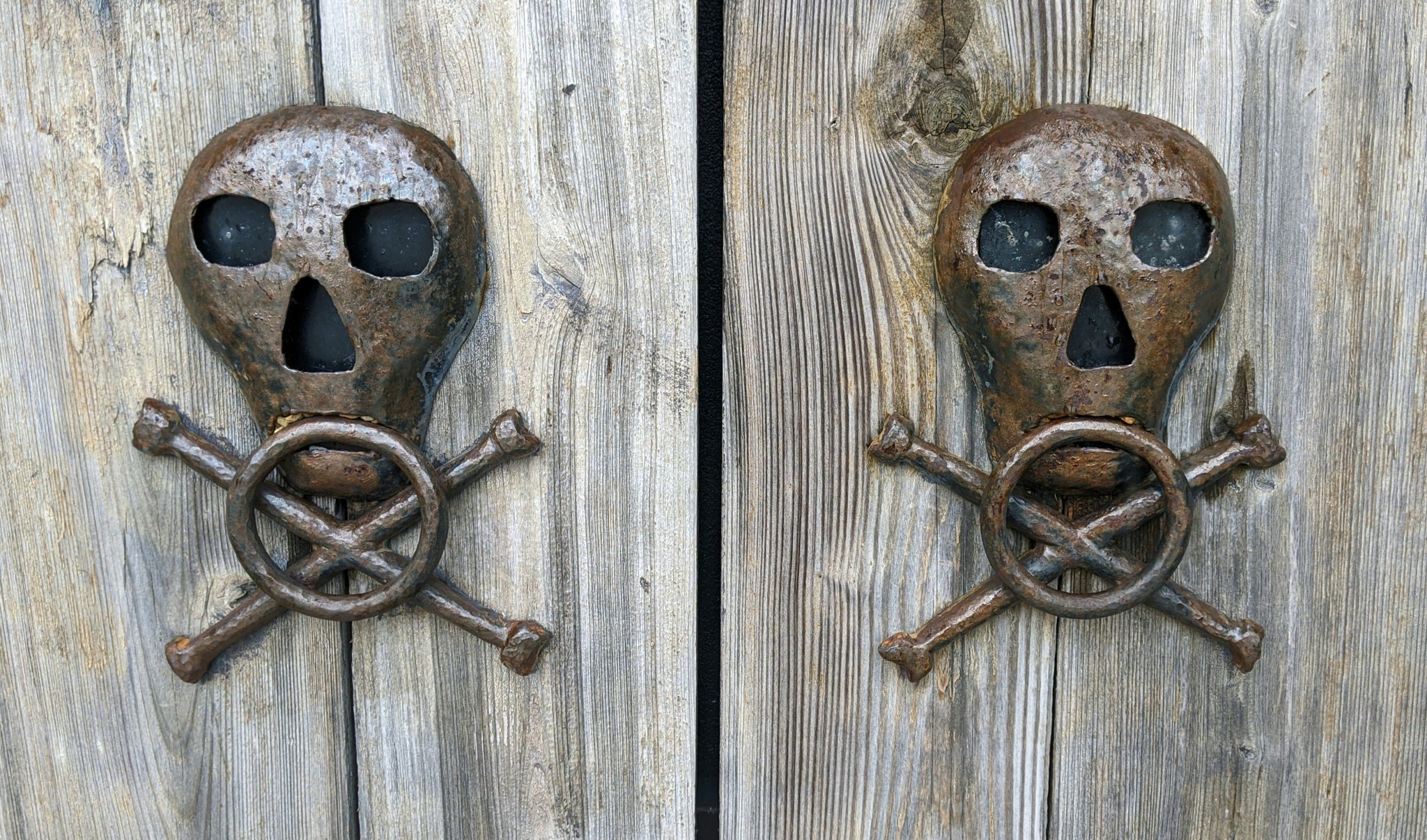 2-tetes-de-morts-en-metal-sur-une-porte-en-bois