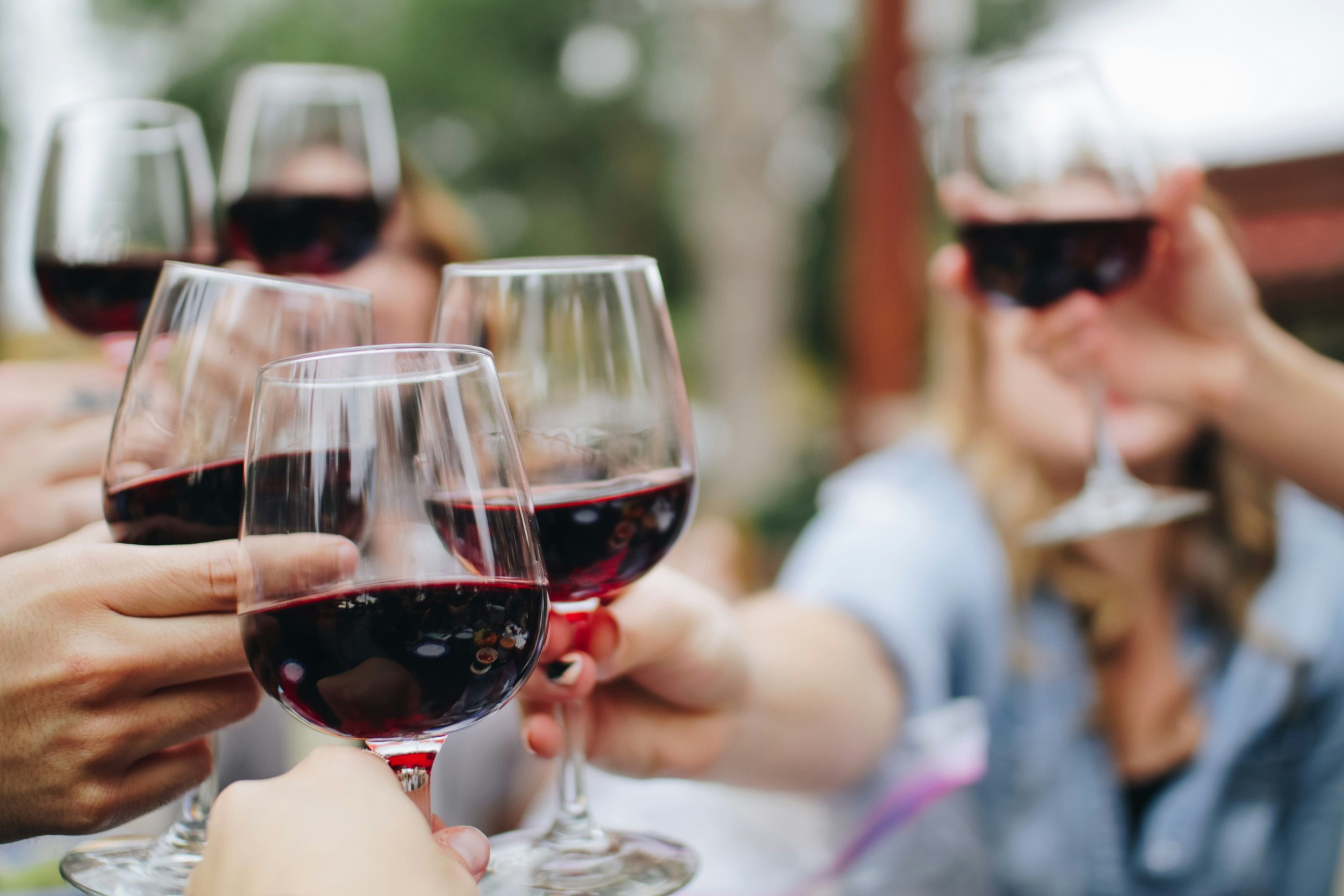 des mains qui trinquent avec des verres de vin