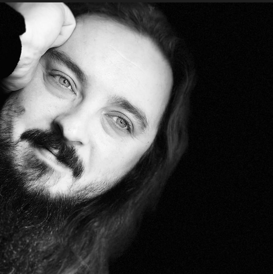 A black and white photo of a man with long hair and a beard.