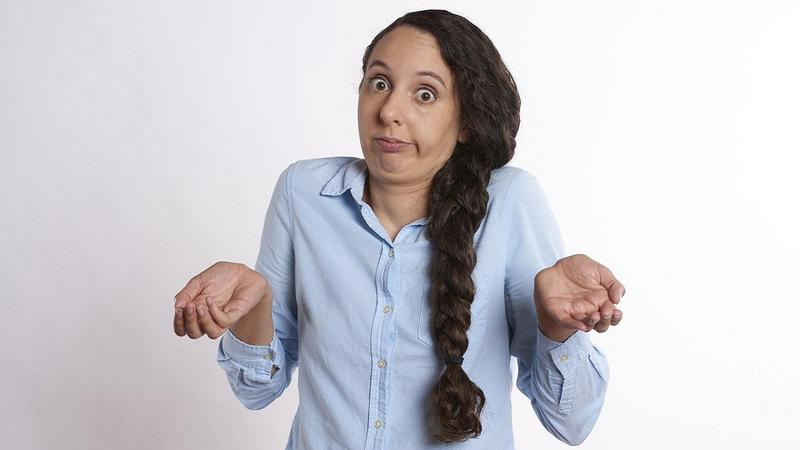 SEO vs GEO: a photo of a caucasian woman with long hair shrugging her shoulders against a pale background.