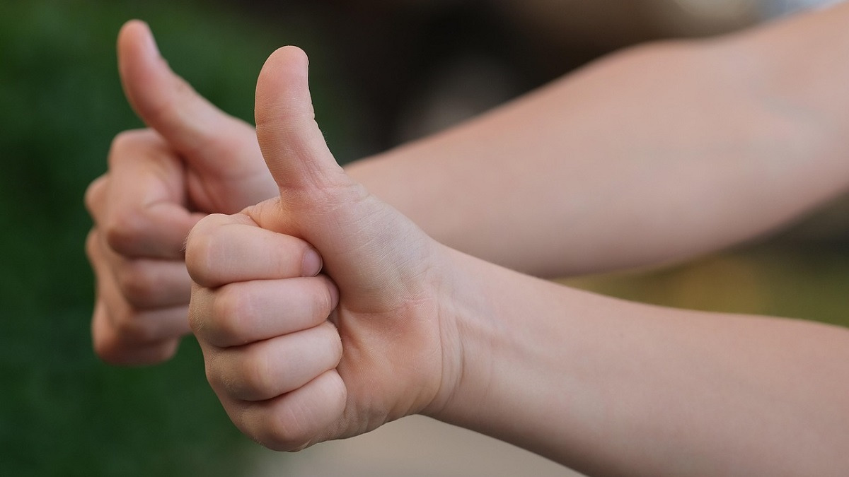 A photo of two caucasian arms doing a thumbs up together.