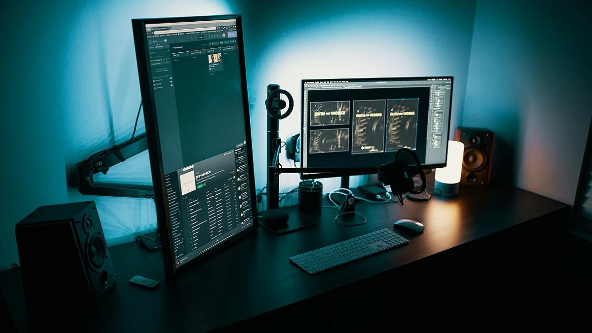 A photo of a PC setup, showing one landscape monitor and one portrait, as well as a blue backlight highlighing the whole thing.