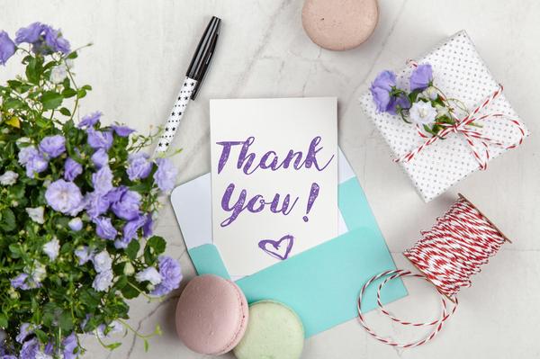 An elegant thank you card with flowers and a gift on a marble surface, perfect for expressing gratitude.