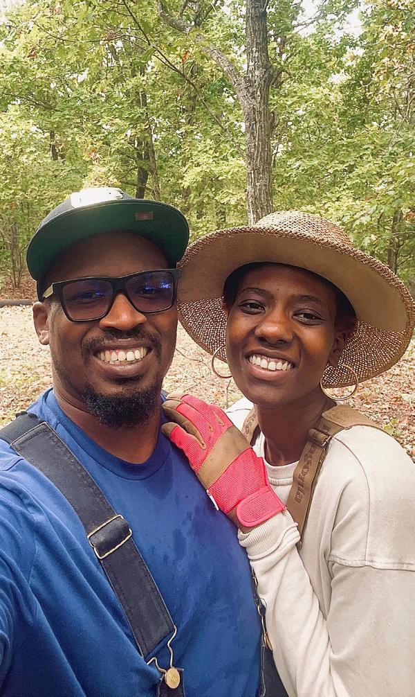 A Black man and woman taking a selfie in a forest