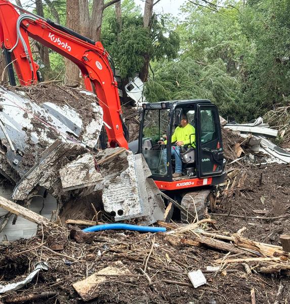 A worker digs through debris along the Guadalupe River