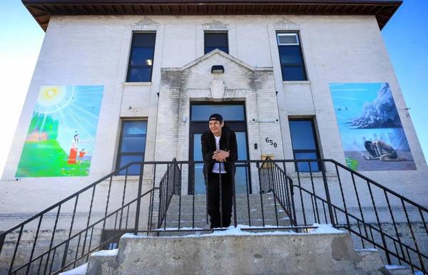 Jedrick Thorassie stands in front of his paintings