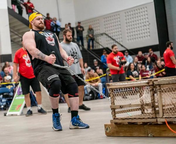 Picture of Andrew Langelaar, a Manitoba man who won the amateur strong man national championships in 2024. He is pulling a heavy wooden crate.